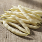 Long slender pale cream white French bean pods on rustic wooden surface in natural sunlight
