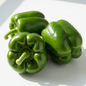 Large glossy bright green capsicum shimla mirch bell peppers on clean white background